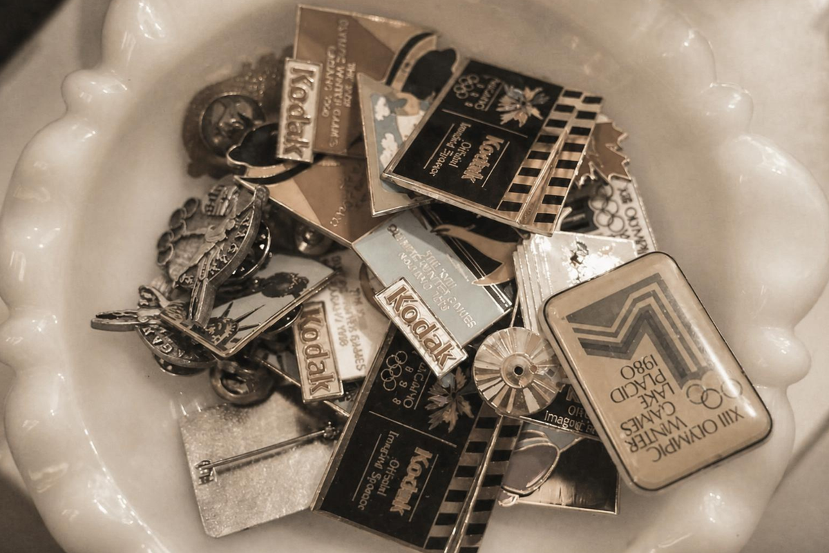 a trinket dish containing vintage enamel pins in a sephia tone